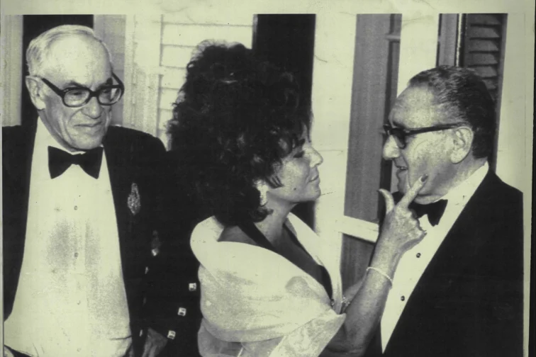 Elizabeth Taylor strokes the cheek of Henry Kissinger as Forbes Magazine publisher Malcolm Forbes looks on at the start of a gala at his estate marking the magazines 70th anniversary in 1987.